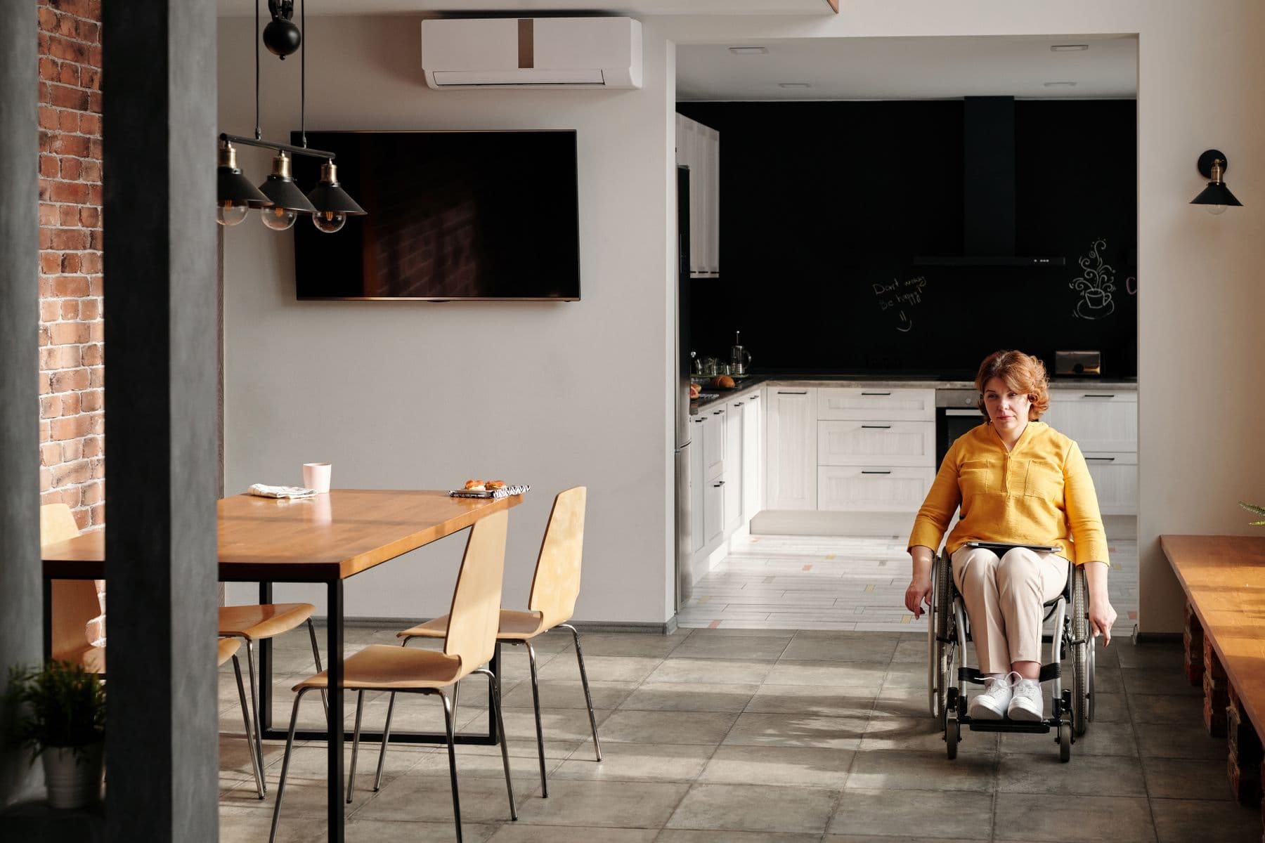 A wheelchair user moving independently through an open kitchen and living space