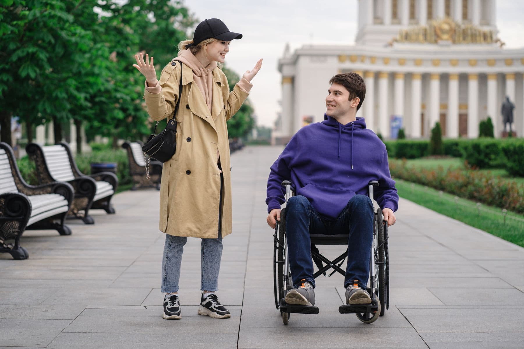 Two friends talking outdoors, including a wheelchair user